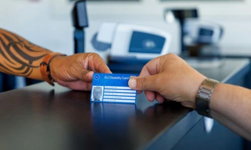 Une personne tend une carte europ&eacute;enne du handicap