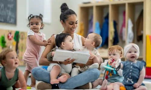 professionnelle lisant une histoire aux enfants dans une cr&egrave;che