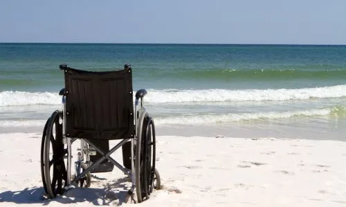 Un fauteuil roulant sur une place de sable blanc.