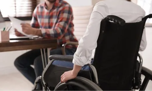 Une femme de dos en fauteuil roulant parle à un homme assis.