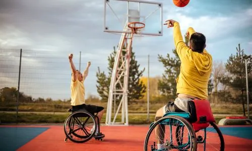 Deux jeunes en fauteuil roulant jouent au basket.