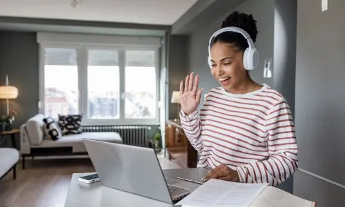 Femme fait le signe «hello» avec sa main à son interlocuteur sur son ordinateur.
