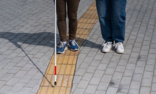 Zoom sur la canne d’une personne aveugle marchant dans la rue.