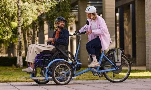 Un homme et une femme sur le tandem avec assise pour un fauteuil roulant.
