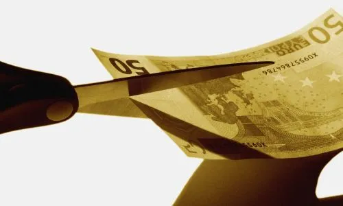 Des ciseaux s’apprêtent à couper un billet de 50 euros.