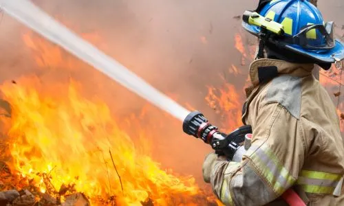 Un pompier de dos utilise sa lance à incendie pour contenir un feu.