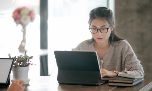 Une femme d’origine asiatique sur son ordinateur dans un bureau.