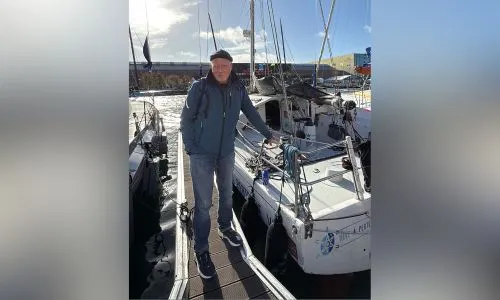 Joël Paris, debout devant son voilier, dans le port du Havre