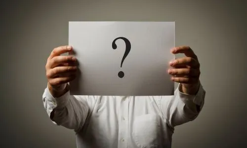 Un homme tient un point d’interrogation devant son visage.