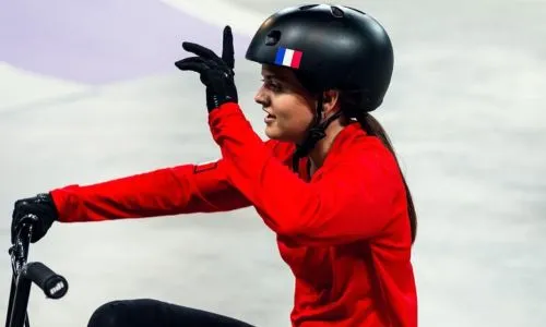 Kenza avec un casque noir et un pull rouge, sur son vélo.