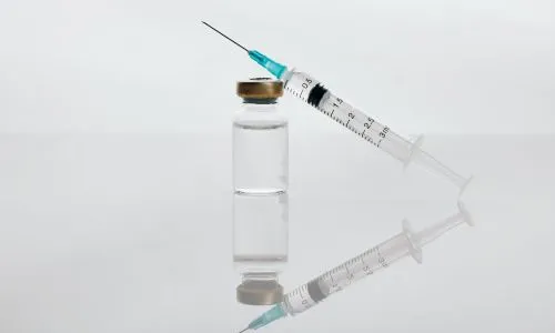 Seringue posée sur un flacon de médicament.