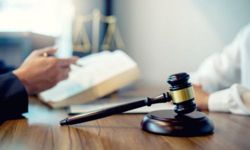 2 personnes échangent à côté du marteau et de la balance de la justice.