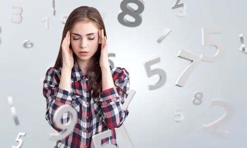 Une jeune fille, entourée de chiffres, ferme les yeux et se tient la tête.