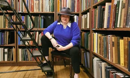 Portrait de Sélina Mills assise dans une bibliothèque.