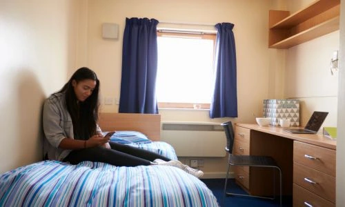 Une &eacute;tudiante sur son t&eacute;l&eacute;phone portable dans sa chambre universitaire.