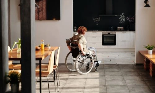Une femme en fauteuil roulant dans sa cuisine