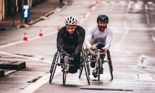 Deux coureurs en fauteuil roulant sur une route.