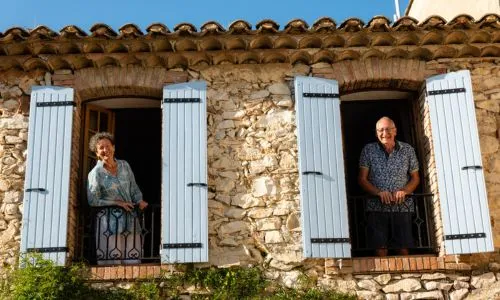 Les propriétaires du Mas de Lanciez chacun à une fenêtre du gîte, souriants.