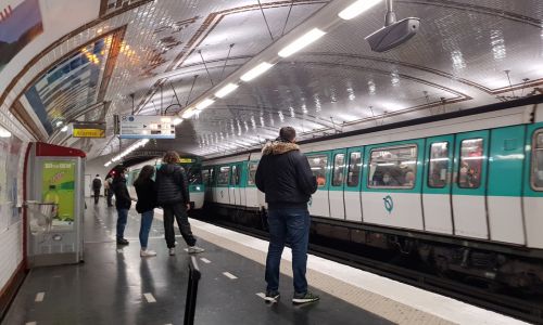 Plusieurs personnes attendent sur le quai du métro à Paris.