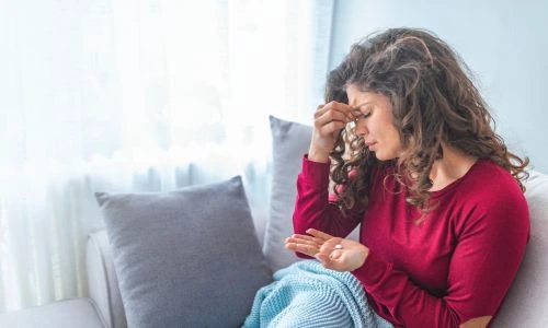 Une femme se tient la t&ecirc;te