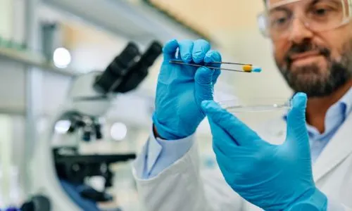 Un chercheur attrape un médicament avec une pince dans un labo.