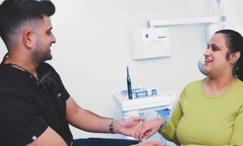 Un dentiste prend la main d’une patiente en situation de handicap.