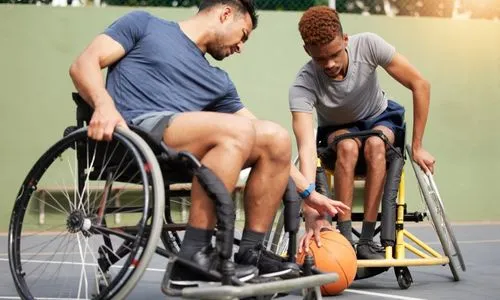 Deux hommes en fauteuil roulant en train de jouer au basket.