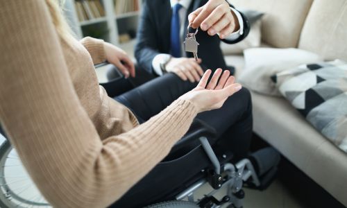 Femme en fauteuil roulant qui récupère la clé de sa location.