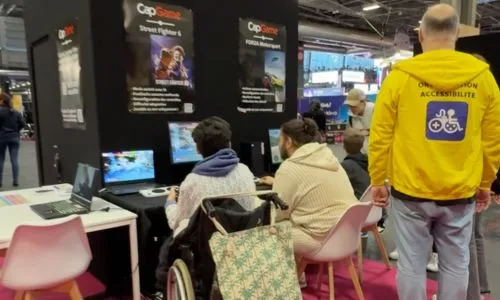 Deux joueurs, dont un en fauteuil roulant, jouent sur un ordinateur.