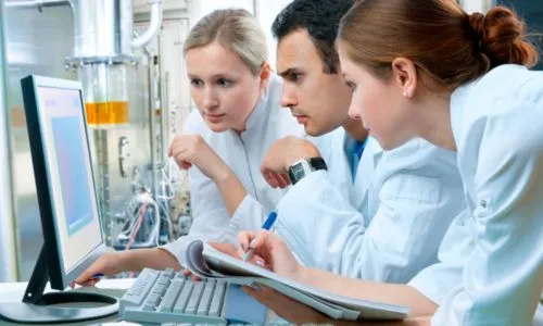 3 scientifiques travaillent sur un ordinateur dans un labo.