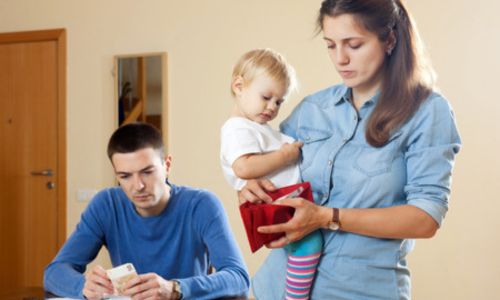 Une mère tient sa fille dans les bras et fouille dans son portefeuille