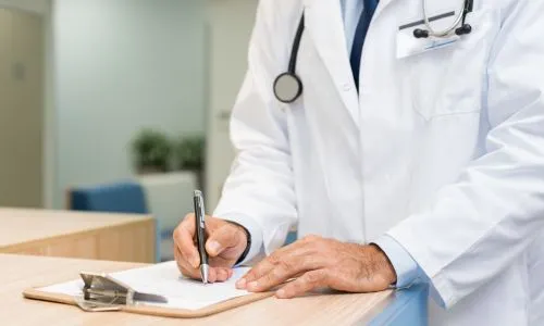 Zoom sur les mains d’un médecin en train d’écrire un rapport médical.