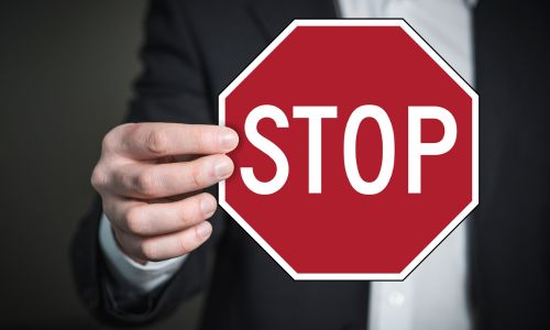 Panneau stop tenu par une main d'homme en costume