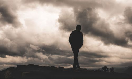 Silhouette d'un enfant de dos marchant sous un ciel d'orage.