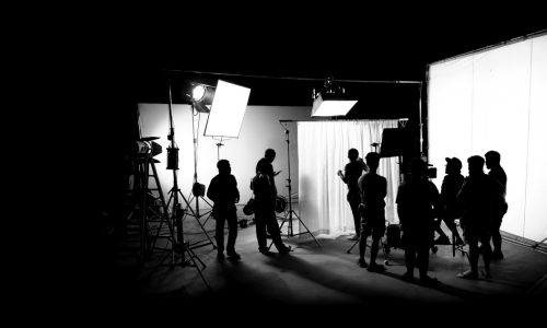 Photo en noir et blanc sur un tournage de film avec une caméra et des éclairages
