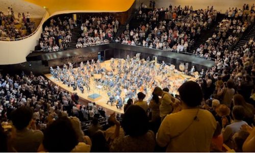 Des spectateurs debout applaudissant l’orchestre de la Philharmonie de Paris.