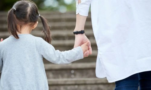 Une petite fille de dos tient la main d&rsquo;un m&eacute;decin