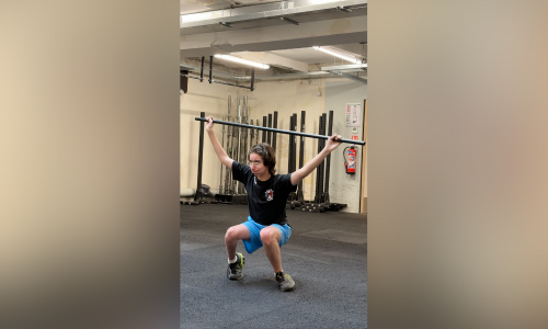 Liam soulève des poids dans la salle de CrossFit.