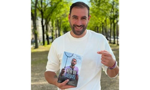 Mathieu Thomas tient son livre dans les mains au milieu d’une allée boisée.