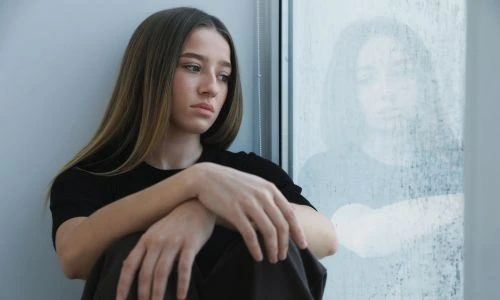 Une adolescente d&eacute;prim&eacute;e devant sa fen&ecirc;tre