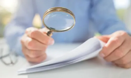 Un homme lit un document avec une loupe.