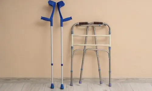 D&eacute;ambulateur et b&eacute;quilles pr&egrave;s d'un mur beige dans une pi&egrave;ce