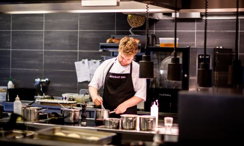 Un jeune homme cuisine dans un restaurant.