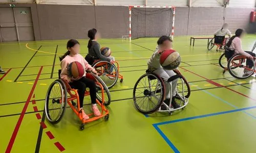 des enfants jouent au basket fauteuil dans un gymnase