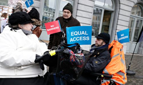 2 personnes en fauteuil tiennent des pancartes «Equal access» (accès égal).
