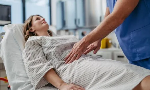 Patiente en séance d’auscultation abdominale avec un médecin.
