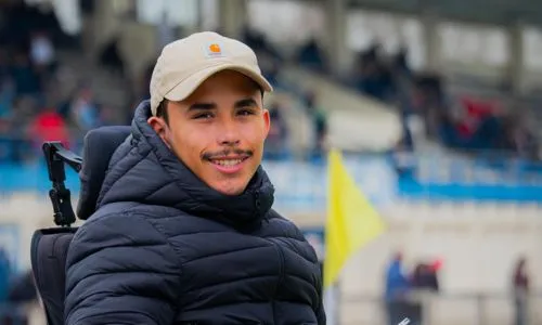 Mathias, en fauteuil roulant, assiste à un match de rugby