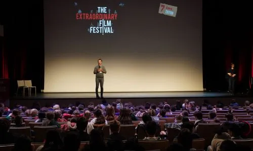 Un homme sur la scène de The extraordinaire film festival s'adresse au public.