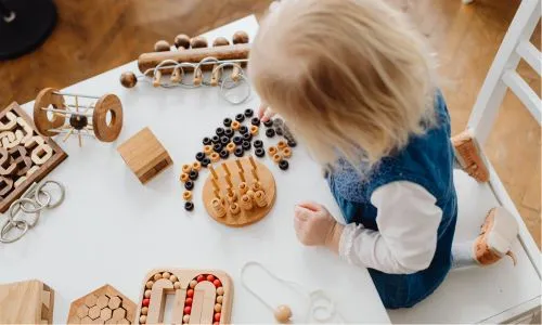 Une petite fille jouant avec des jouets en bois sur une table