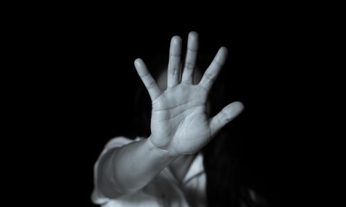 Photo en noir et blanc d’une personne faisant le signe stop avec sa main.